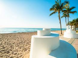 Aesthetic Florida beach scene with palm trees, golden sunset over the ocean, and calm tropical waves, representing travel lifestyle and Instagram captions inspiration.
